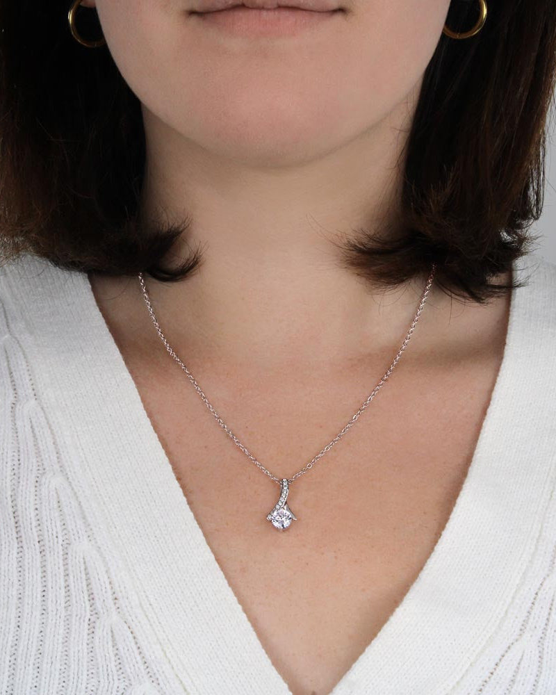 Close-up of a person wearing a silver necklace with a pendant.